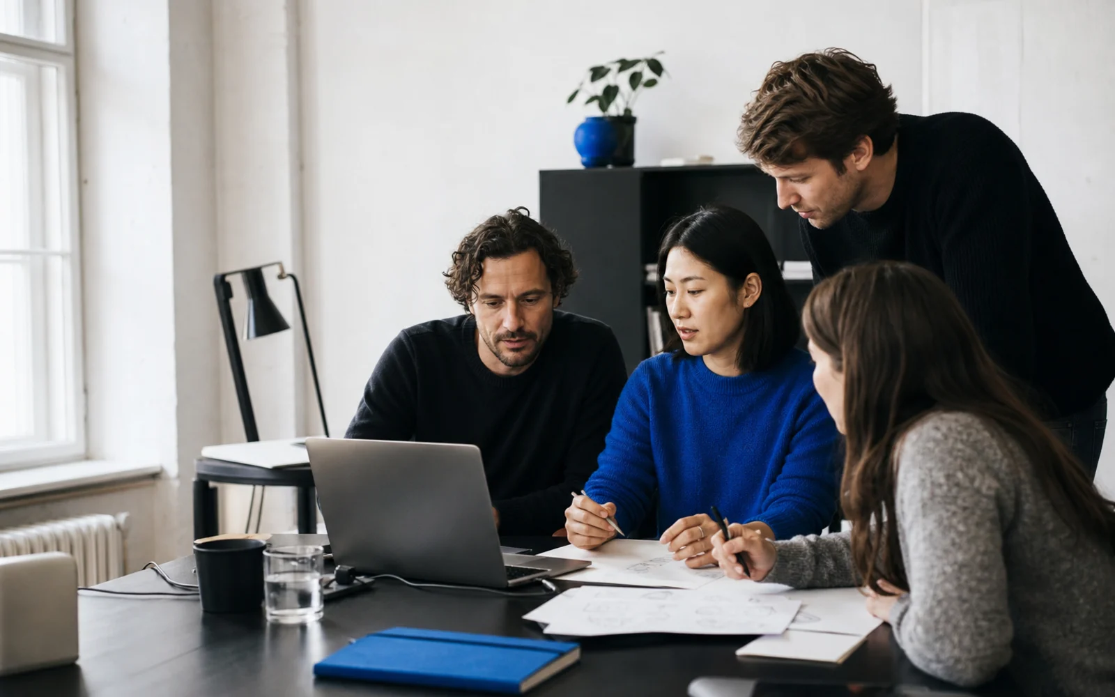 A software product team collaborating around a laptop and project sketches
